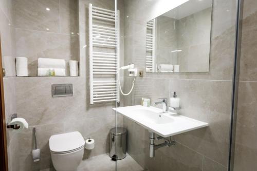 a bathroom with a sink and a toilet and a mirror at King's Resort - casino and hotels in Rozvadov
