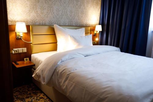 a large bed in a hotel room with two lamps at King's Resort - casino and hotels in Rozvadov
