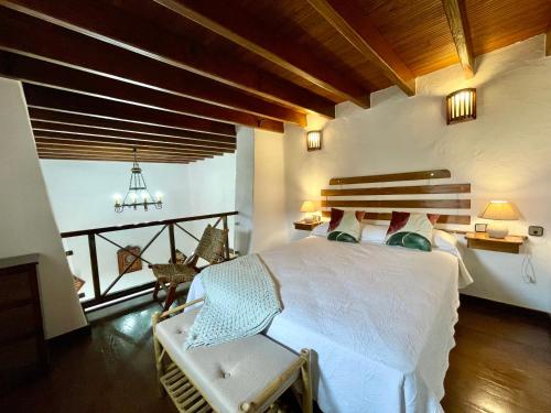 Un dormitorio con una cama blanca y un balcón. en Casa montaña Tamia, en Muñique