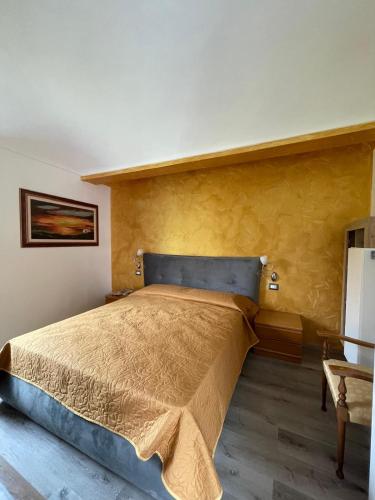 a bedroom with a large bed with a yellow wall at Villa Maria in Occhieppo Inferiore