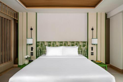 a bedroom with a large white bed with two lamps at Mandarava Resort and Spa, Karon Beach in Karon Beach