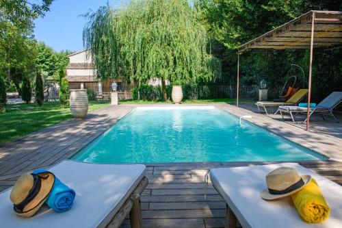 - une piscine avec deux casquettes assises sur une table à côté dans l'établissement Mas Gaffet, à Saint-Rémy-de-Provence