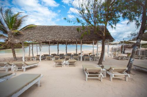 a beach with a bunch of chairs and trees at AHG Lion Beach Resort in Watamu