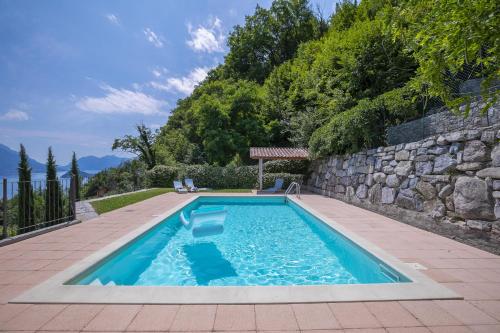 a swimming pool in a yard with a stone wall at Parco dei Cervi Terrazzo in Plesio