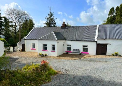 a white house with a black roof and pink accents at Corderry Farmhouse, idyllic cottage amid 250 acres in Stagdale Bridge