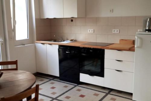 Il comprend une cuisine équipée d'une cuisinière et d'un lave-vaisselle noir. dans l'établissement A Carolles, maison idéale pour des vacances Nature, à Carolles