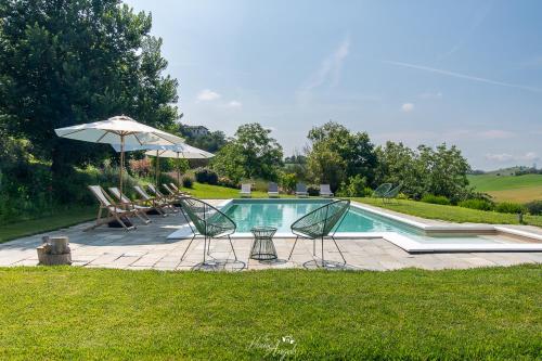 a swimming pool with chairs and an umbrella at Villa Fiori B&B in Moncalvo