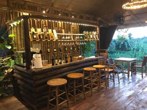 a bar with wooden stools and bottles of wine at Bamboo Eco Village in Can Tho
