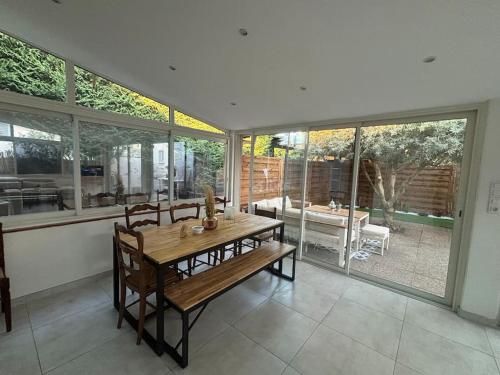 Un comedor con mesa y sillas y ventanas. en Villa Centre Mandelieu-la-Napoule, en Mandelieu-la-Napoule