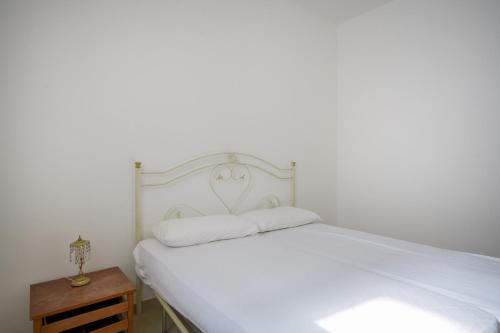 a white bed with a white headboard and a night stand at Beach House , Torre Canne - Dori in Torre Canne