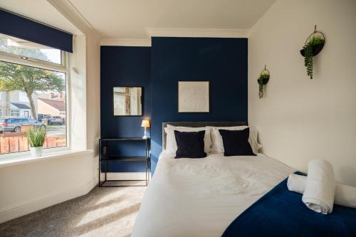 een blauwe en witte slaapkamer met een bed en een raam bij Lime House By Horizon Stays in Redcar