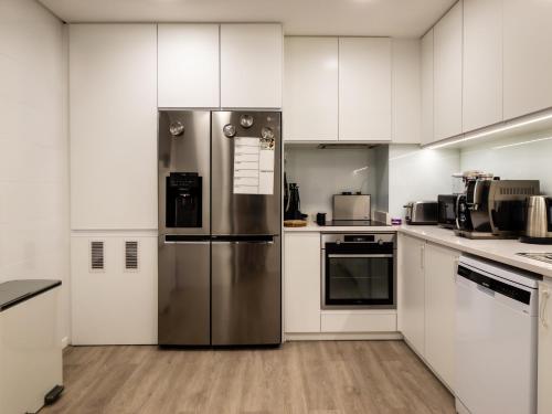 a kitchen with white cabinets and a stainless steel refrigerator at Azzurro at Sea in São Roque