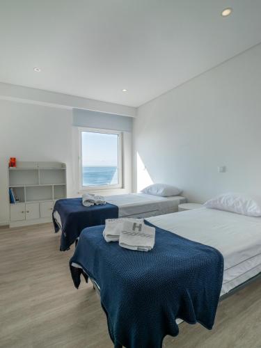 a bedroom with two beds and a window at Azzurro at Sea in São Roque