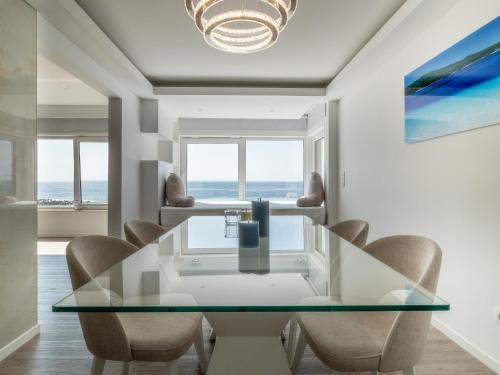 a dining room with a glass table and chairs at Azzurro at Sea in São Roque