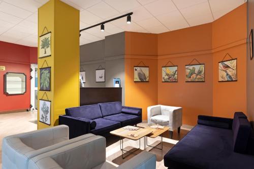 a living room with blue couches and orange walls at B&B Hotel Como City Center in Como
