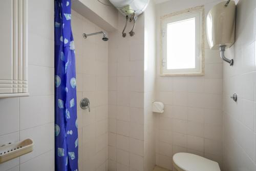 a bathroom with a toilet and a blue shower curtain at Beach House , Torre Canne - Nemo in Torre Canne