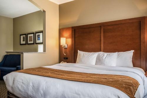 a hotel room with a large bed and a chair at Comfort Suites Near Texas State University in San Marcos