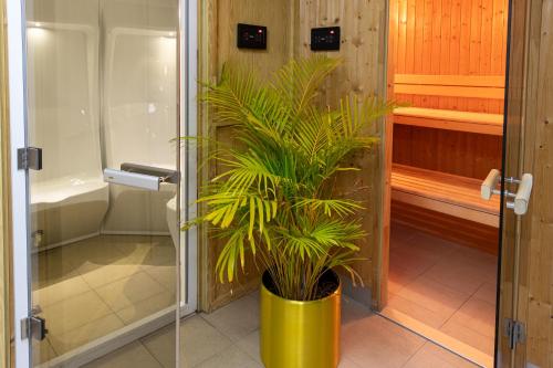 a plant in a yellow pot in a bathroom at Wonder Palace Hotel Qatar in Doha