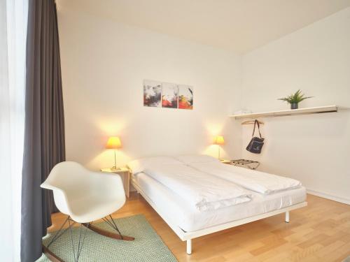a white bedroom with a white bed and a chair at Apartments by Hotel Astoria in Olten