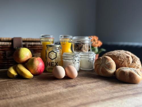 a table with apples eggs bread and jars of food at Bed & Breakfast Voor De Wind in Slootdorp