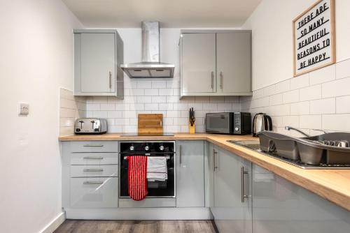 a kitchen with stainless steel appliances and white cabinets at Smart 1 Bedroom Apartment in Central Rotherham in Rotherham
