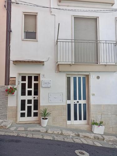 ein weißes Gebäude mit zwei Türen und einem Balkon in der Unterkunft Sidella home in Ginosa