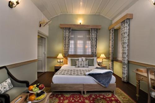 a bedroom with a bed and a couch and a window at Brij Villa, Dalhousie - A Colonial Luxury Retreat in Dalhousie