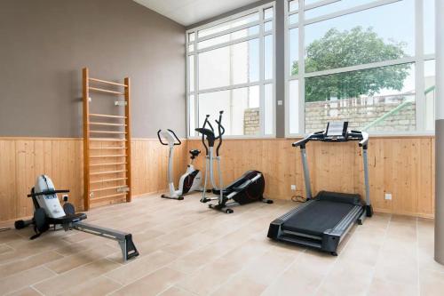 a gym with several exercise equipment in a room with windows at Appartement terrasse centre Saint Martin in Saint-Martin-de-Ré