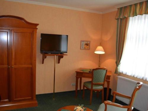 una camera d'albergo con scrivania e TV a schermo piatto di Pension Alter Kutschenbauer a Wernigerode