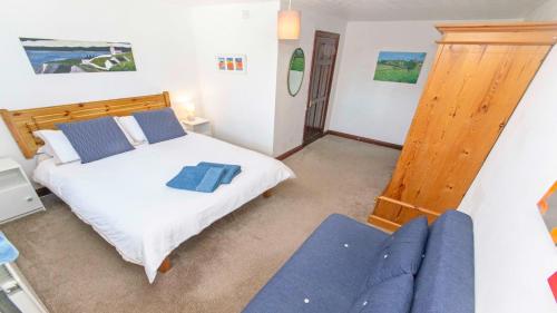 a bedroom with a bed and a blue couch at Rockham Bay View - Sleeps 6 Mortehoe in Mortehoe