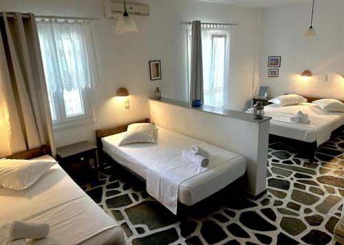 a room with three beds and two windows at Nostos Studios in Parikia