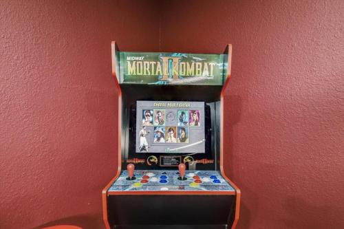 a toy machine with a video game on a wall at Luxurious 5BR 2BA Holiday Home with Pool, Grill, Sauna & Game Room in The Colony