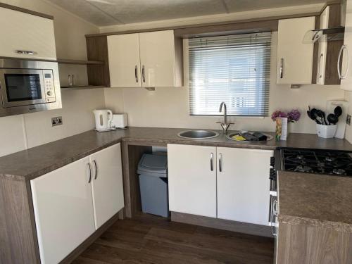 a kitchen with white cabinets and a sink at 59 Cliff Field in Hopton on Sea