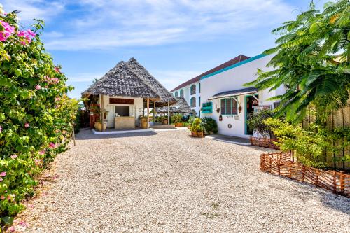 a driveway leading to a building with a thatched roof at AHG Sun Bay Mlilile Beach Hotel in Matemwe