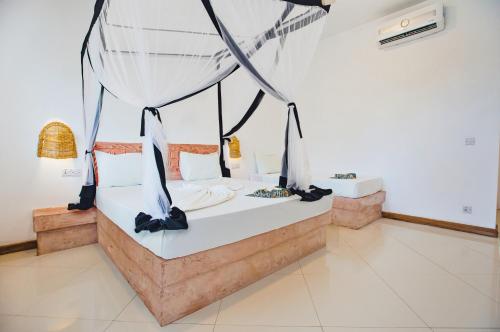 a bedroom with a bed with a mosquito net at AHG Sun Bay Mlilile Beach Hotel in Matemwe