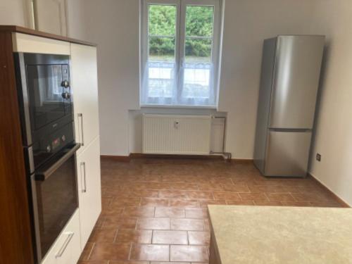 a kitchen with a refrigerator and a tile floor at Apartmán Monika in Kraslice
