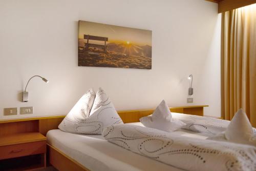 a bed with white pillows and a picture on the wall at Bed and Breakfast Ederhof in San Giacomo