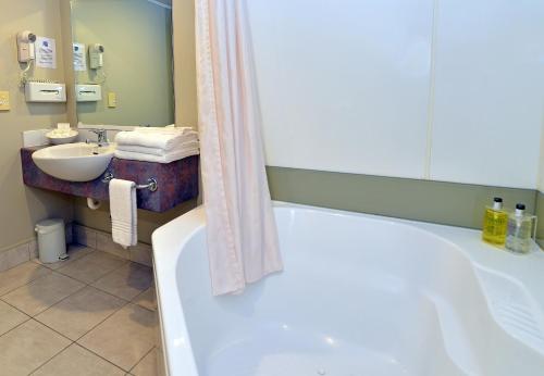 a bathroom with a tub and a sink at Brougham Heights Motel in New Plymouth