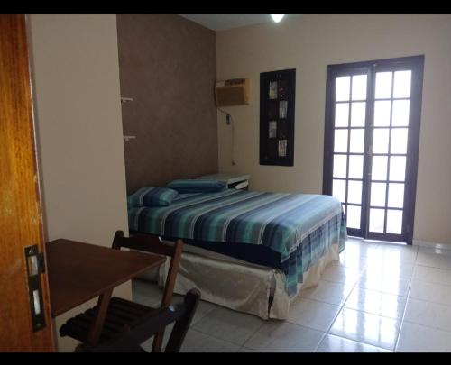 a bedroom with a bed and a table and a window at RECANTO PARAISO in Ubatuba