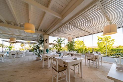 a restaurant with white tables and chairs and large windows at Tenuta Centoporte in Otranto