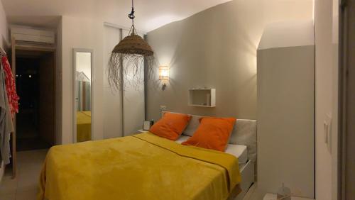une chambre avec un lit avec des oreillers orange dans l'établissement Charmante petite maison dans résidence avec piscine chauffée à 600 m de la plage, à Belgodère