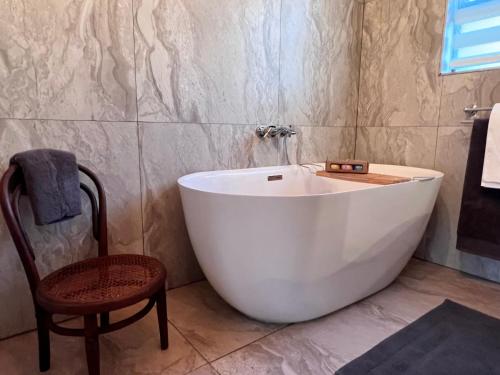 a large white tub in a bathroom with a chair at Walnut Cottage in Clarens