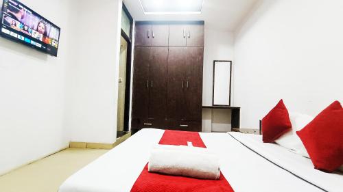 a bedroom with a bed with red pillows and a television at Hotel Maharaja Inn By The Premium Villa in New Delhi