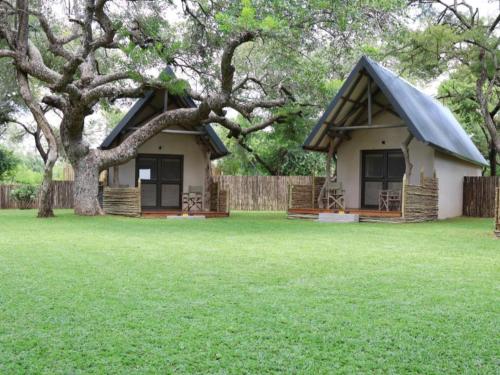 a small house with a tree in the yard at Leopard's Bend Bush Lodge in Hoedspruit
