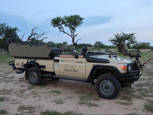 a tan jeep parked in a field at Leopard's Bend Bush Lodge in Hoedspruit