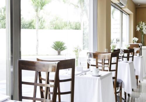 a restaurant with white tables and chairs and a large window at Mision Express Merida Altabrisa in Mérida