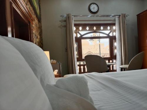a bedroom with a bed and a window with a clock at Durrat Nizwa Inn in Nizwa
