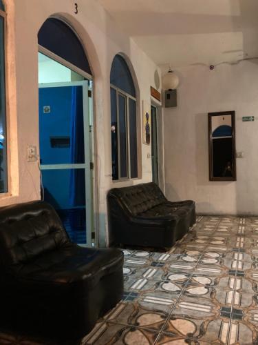 a living room with two leather chairs and a blue door at Mandala’s Hostal in San Pedro La Laguna
