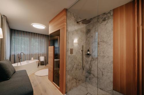 a bathroom with a walk in shower and a tub at Bad Ratzes in Siusi