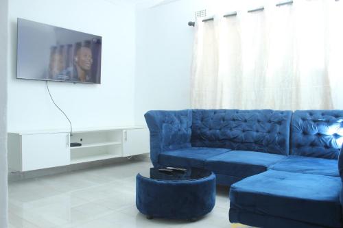 a living room with a blue couch and a tv at Blantyre Airport Lodge in Chileka